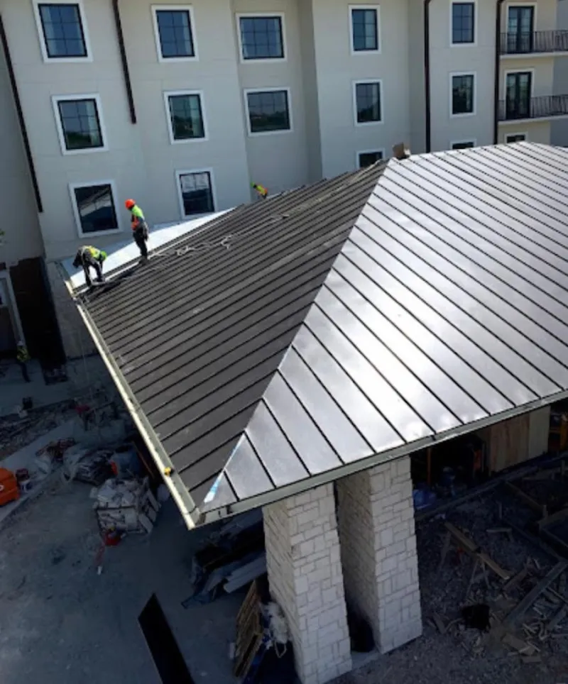 Crew installing standing seam metal roof panels on a commercial project in Kennett